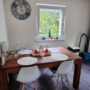 a dining room table with white chairs and a clock on the wall at FeWo Tanja in Lindau