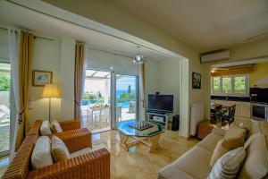 ein Wohnzimmer mit einer Couch, einem Fernseher und einem Tisch in der Unterkunft Villa Hera-The infinity blue in Nisaki