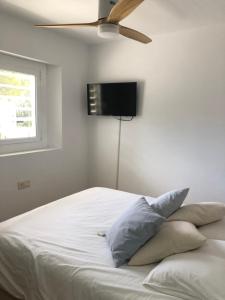 1 dormitorio con 1 cama blanca y ventilador de techo en Espectacular apartamento con piscina en Calella de Palafrugell, en Calella de Palafrugell