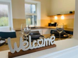 una mesa con 2 copas de vino y un cartel de bienvenida en New North House by Staytor Accommodation, en Exeter