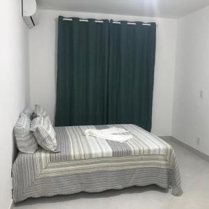 a bed in a room with a green curtain at Refugio Villa Verona Praia do Forte in Mata de Sao Joao
