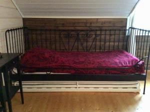 una cama de metal con una manta roja encima en Purola Farm Guesthouse, en Saarijärvi