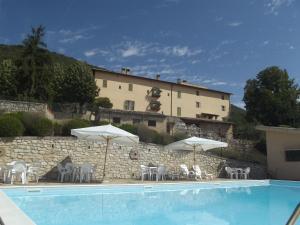 a pool with chairs and umbrellas in front of a building at Agriturismo Villa Gabbiano in Capodacqua