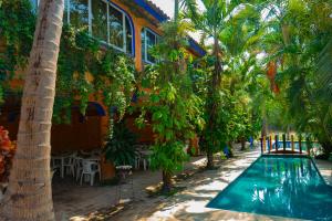a swimming pool in front of a building with palm trees at Balneario y Cabañas ISIS in La Huerta