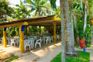 a restaurant with tables and chairs and palm trees at Balneario y Cabañas ISIS in La Huerta