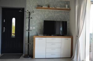 ein Wohnzimmer mit einem TV auf einem Schrank und einer Tür in der Unterkunft Domki na Wzgórzu - Rospuda in Filipów