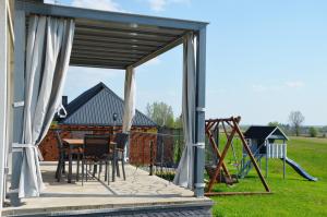a pavilion with a table and chairs and a playground at Domki na Wzgórzu - Rospuda in Filipów