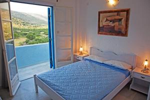 a bedroom with a bed and a large window at St.George Valsamitis in Katapola