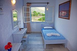 a small bedroom with a bed and a window at St.George Valsamitis in Katapola