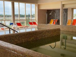 basen w budynku ze stołami i krzesłami w obiekcie Bike & Spa Velence Apartman w mieście Velence