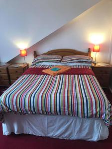 a bed with a colorful striped comforter in a bedroom at Broomlea Guest House in Dyce