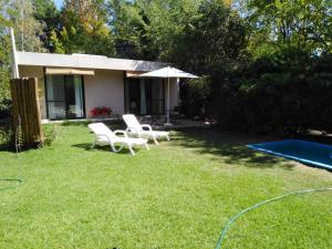 einen Garten mit Stühlen, einem Sonnenschirm und einem Pool in der Unterkunft Mini casa in Chacras de Coria