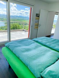 Bett in einem Zimmer mit einem großen Fenster in der Unterkunft Villa au bord du lac de Morat avec vue imprenable in Bellerive
