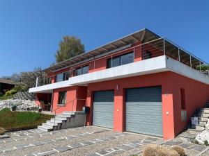 a red house with two garage doors in front of it at Villa au bord du lac de Morat avec vue imprenable in Bellerive