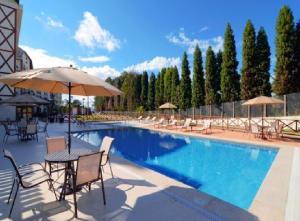 佩德拉阿祖爾的住宿－Condomínio Vista Azul hotel，一个带桌椅和遮阳伞的游泳池
