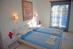 a bedroom with a bed with blue sheets and a window at St.George Valsamitis in Katapola