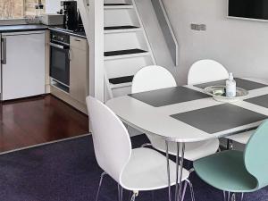 a kitchen with a table and white chairs in a room at 5 person holiday home in V ggerl se in Marielyst