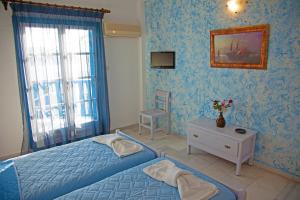 a blue bedroom with a bed and a chair at St.George Valsamitis in Katapola