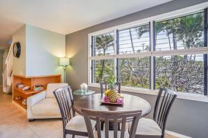 a living room with a table and chairs and windows at Makahuena at Poipu in Koloa