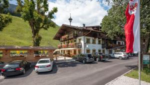 un gran edificio con coches estacionados en un estacionamiento en Gasthof Oberstegen, en Söll