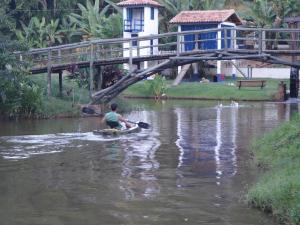 a man riding a paddle board in the water under a bridge at Estancias Duvivier Hotel Fazenda in Três Rios