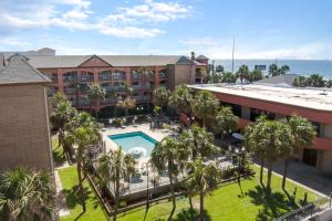 an aerial view of a hotel with a pool and palm trees at Beachfront Palms Hotel Galveston in Galveston