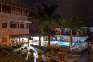 an outdoor swimming pool with palm trees and a hotel at Pousada Pesque Park in Boracéia