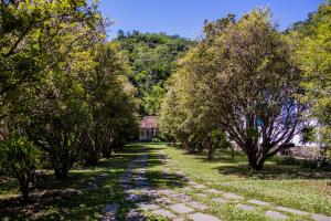 a path with trees and a house in the distance at Estancias Duvivier Hotel Fazenda in Três Rios