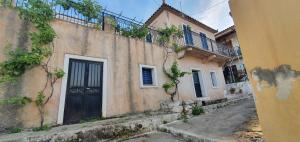 an old building with a black door on a street at Traditional Hillside Cottage in Gythio