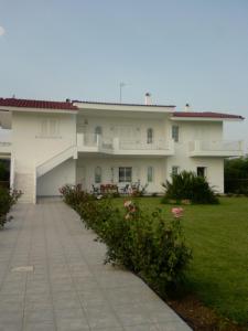 Silver villa Raches maisonette & Green في Kouvéla: مبنى أبيض كبير مع ساحة عشب