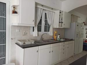 a kitchen with white cabinets and a sink and a refrigerator at Silver villa Raches maisonette & Green in Kouvéla +167 photos