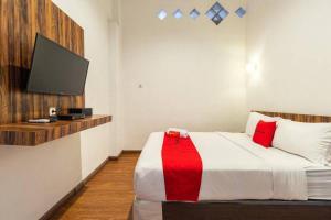 a bedroom with a bed with a tv on the wall at RedDoorz near RS Royal Prima Medan 2 in Medan
