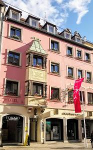 un bâtiment rose avec un drapeau rouge devant lui dans l'établissement Zum Winzermännle, à Wurtzbourg