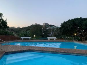 uma grande piscina azul com dois bancos à volta em 901 Umdloti Beach Resort em Umdloti