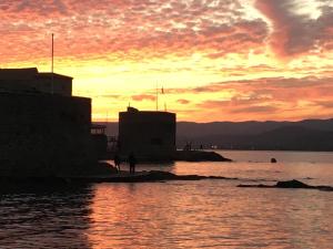 a sunset over the water with people walking on the beach at Stone studio in Saint-Tropez