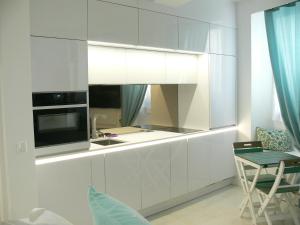a kitchen with white cabinets and a table and a chair at Stone studio in Saint-Tropez