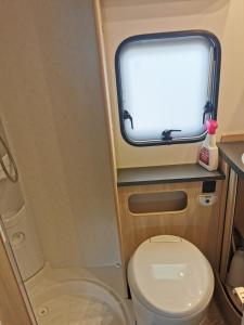 a small bathroom with a toilet and a window at CAMPING LES HERLEQUINS in Losne