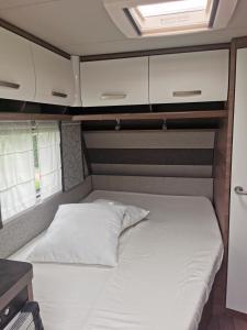 uma cama na parte de trás de uma caravana em CAMPING LES HERLEQUINS em Losne