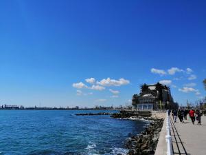 a group of people walking along a pier next to the water at Promenada Apartment in Constanţa