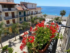 een balkon met rode bloemen en een strand bij Casa stile mediterraneo Piazza Durante a Letojanni Taormina in Letojanni