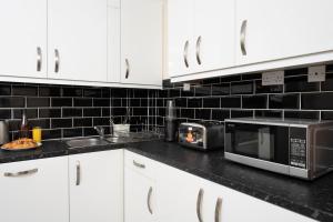 cocina con armarios blancos y microondas en Single Room G1 (Sandycroft Guest House), en Londres