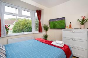 a bedroom with a blue bed and a tv at Economy Double Room G2 (Sandycroft Guest House) in London