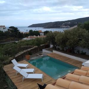 a swimming pool with two white chairs and a view of the ocean at Casa Margot2 in Cadaqués