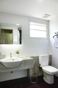 a bathroom with a sink and a toilet and a mirror at The September Salaya in Salaya