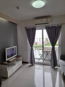 a living room with a tv and a large window at The September Salaya in Salaya