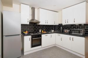 una cocina blanca con armarios y electrodomésticos blancos en F4 Modern Double Room (Sandycroft Guest House), en Londres