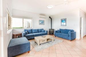 a living room with two blue couches and a table at Canal Rocks Beachfront Apartments in Yallingup