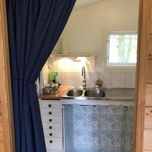 a kitchen with a sink and a blue curtain at Stuga utanför Fjällbacka in Fjällbacka