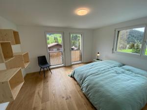 a bedroom with a bed and a desk and two windows at Horizon 5 in Schwarzsee