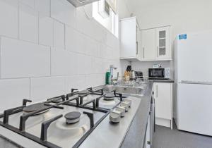 a white kitchen with a stove and a refrigerator at The Old Brewery House - By My Getaways - Free Parking in Brighton & Hove